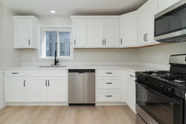 a kitchen with white cabinets and stainless steel appliances