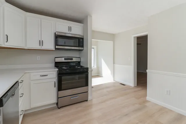 a kitchen with granite countertop white cabinets and stainless steel appliances