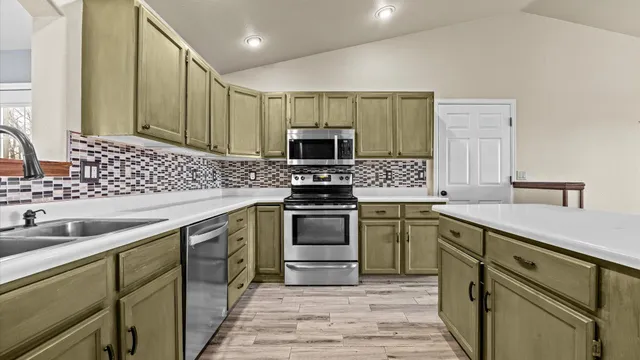 a kitchen with kitchen island a sink stainless steel appliances and cabinets