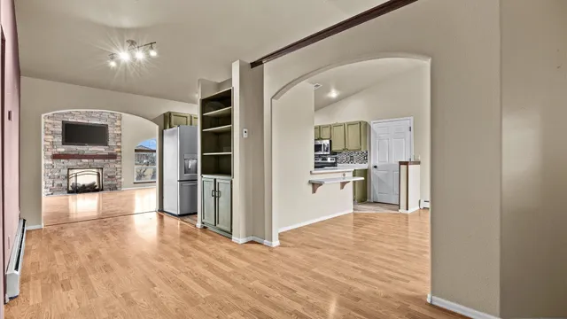 a view of an empty room with a window and wooden floor