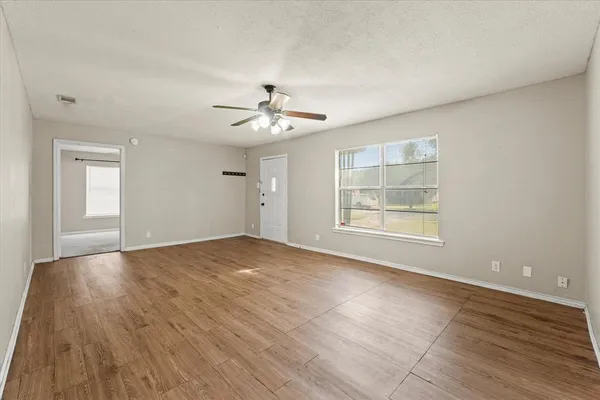 a view of an empty room with a window and wooden floor