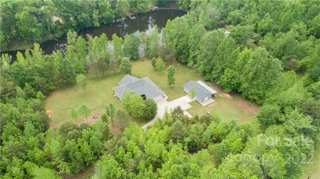 an aerial view of residential house with outdoor space and trees all around