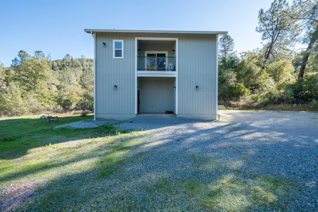 a living room with couches kitchen view and a refrigerator