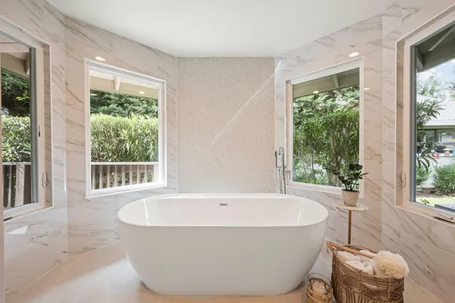 a white bath tub sitting in a bathroom next to a window