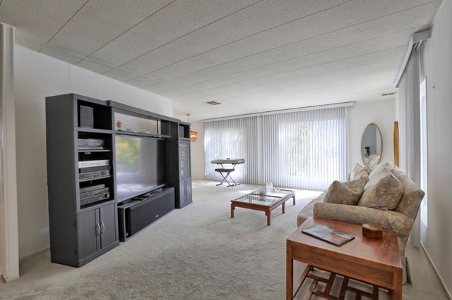 a living room with furniture a kitchen view and a flat screen tv