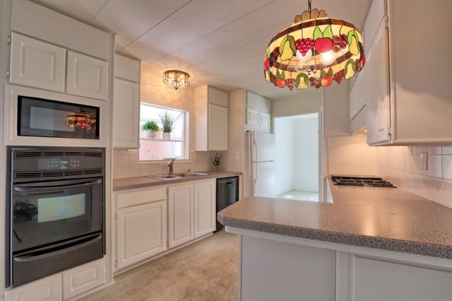 a kitchen with stainless steel appliances granite countertop a stove a sink and a microwave
