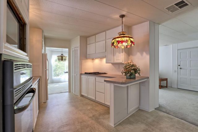 a room with kitchen island stainless steel appliances and chandelier