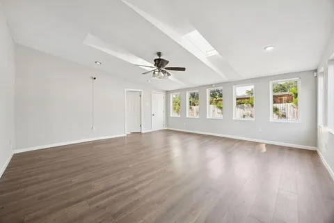a view of an empty room with wooden floor and a window