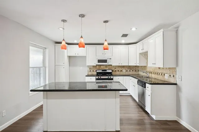 a kitchen with kitchen island granite countertop stainless steel appliances and white cabinets