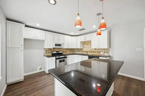 a kitchen with stainless steel appliances granite countertop a sink a stove and a wooden floor
