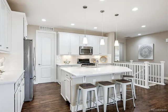 a kitchen with stainless steel appliances granite countertop a kitchen island hardwood floor and a sink
