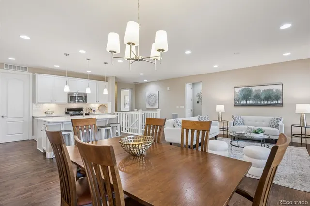a dining room with wooden floor a chandelier a wooden table and chairs