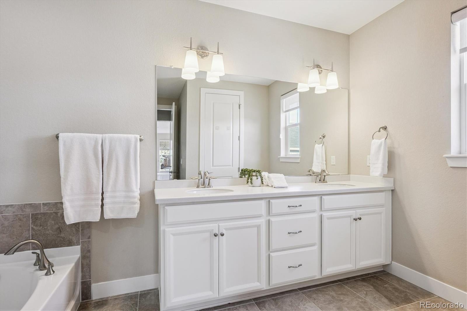 6667 Club Villa Road Parker, CO 80134 - Photo 24 of 50 a spacious bathroom with a double vanity sink mirror and bathtub