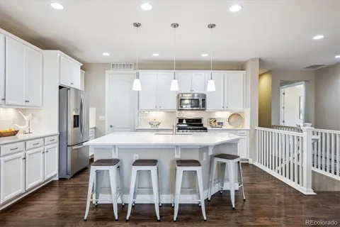 a large kitchen with kitchen island granite countertop a dining table chairs and white cabinets