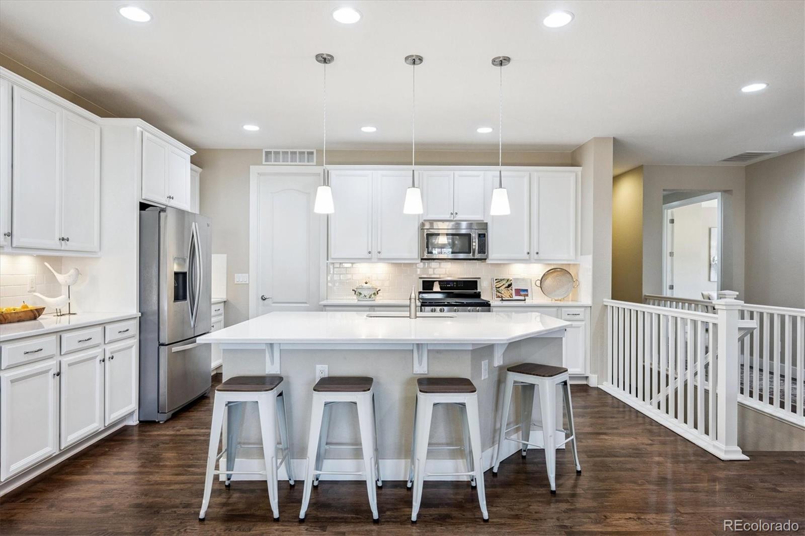 6667 Club Villa Road Parker, CO 80134 - Photo 10 of 50 a large kitchen with kitchen island granite countertop a dining table chairs and white cabinets