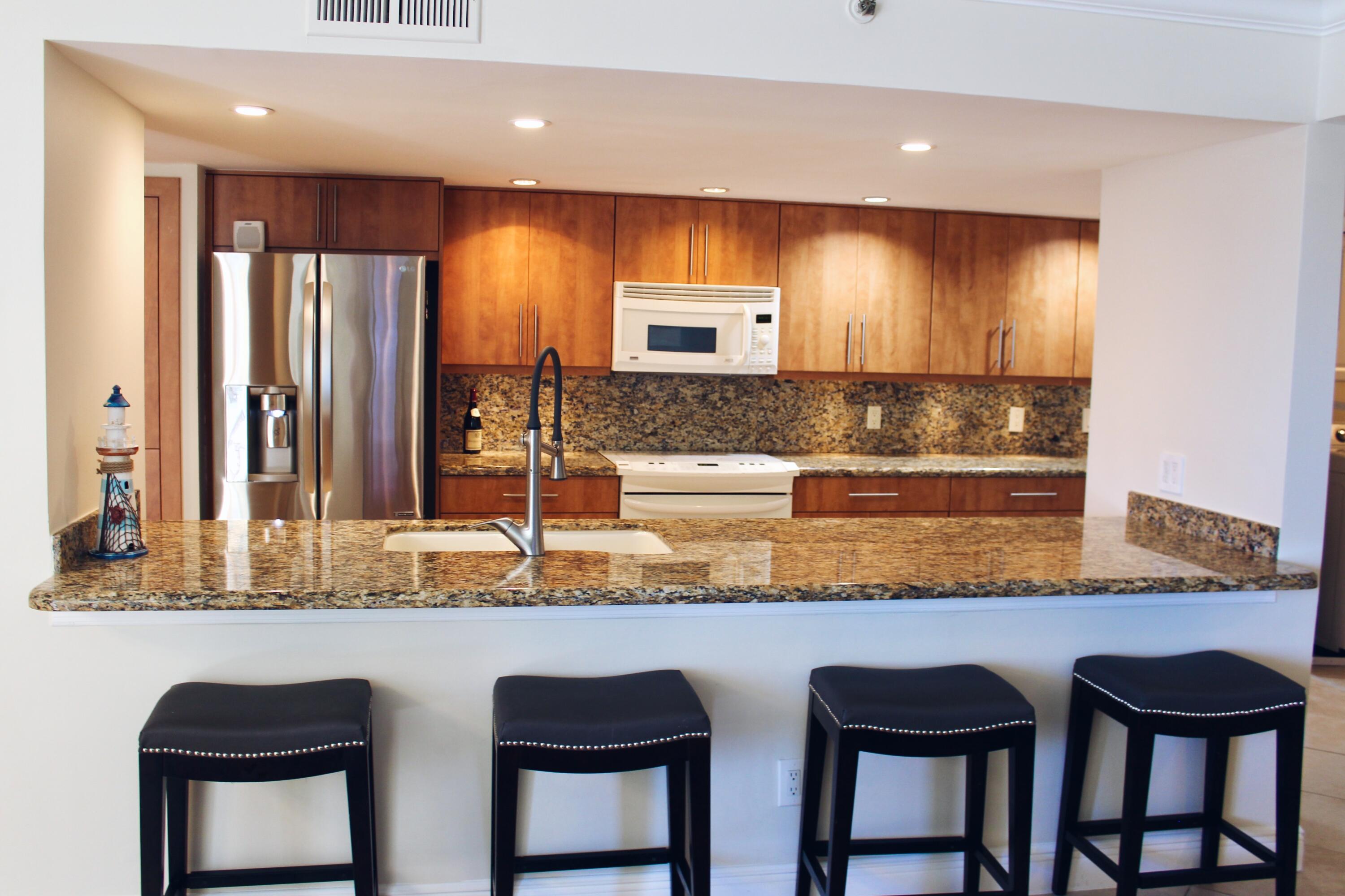 1915 Lavers Circle, Unit E209 Delray Beach, FL 33444 - Photo 12 of 20 a kitchen with granite countertop a sink and chairs
