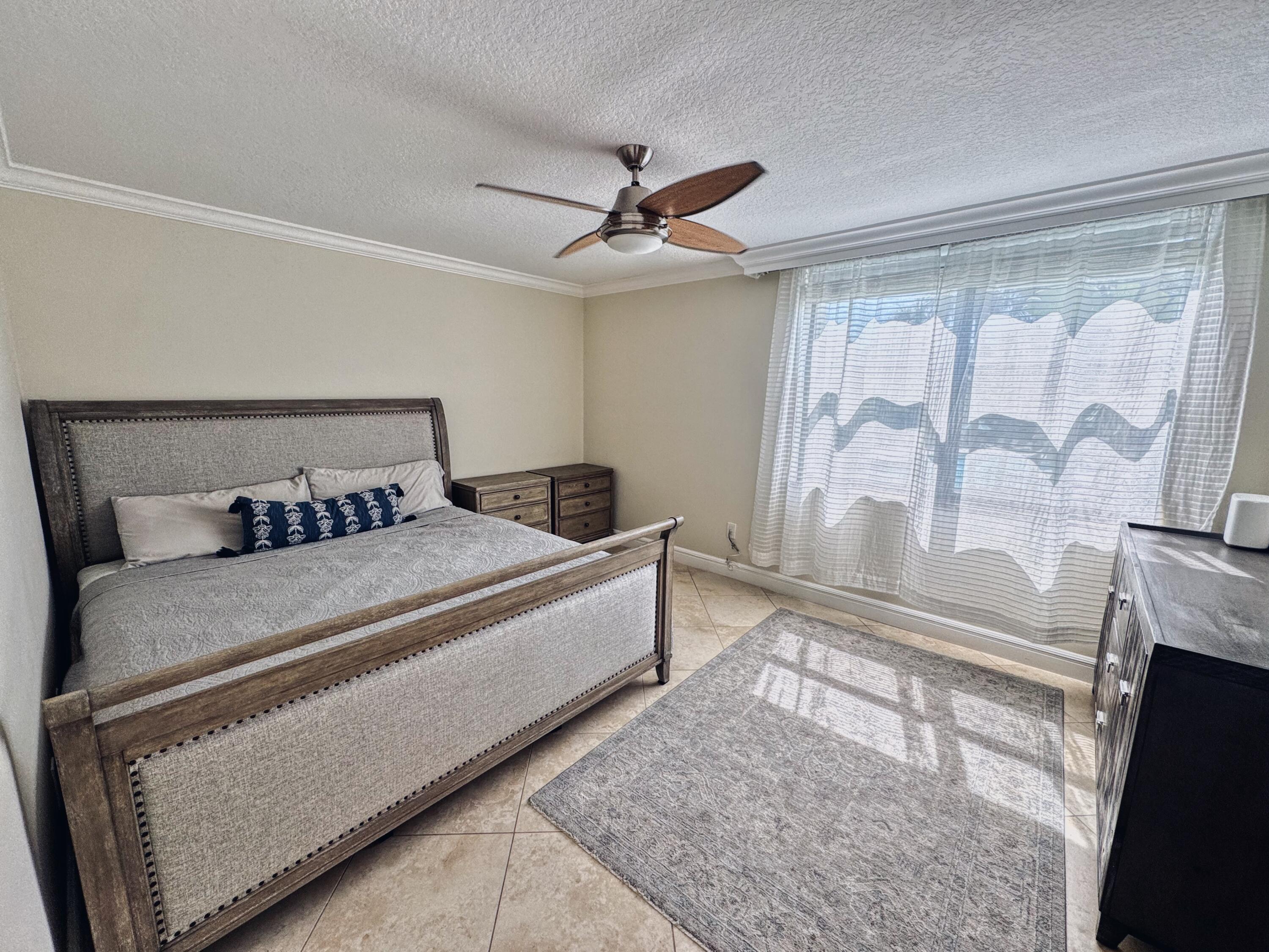 1915 Lavers Circle, Unit E209 Delray Beach, FL 33444 - Photo 13 of 20 a bedroom with a bed and a fireplace