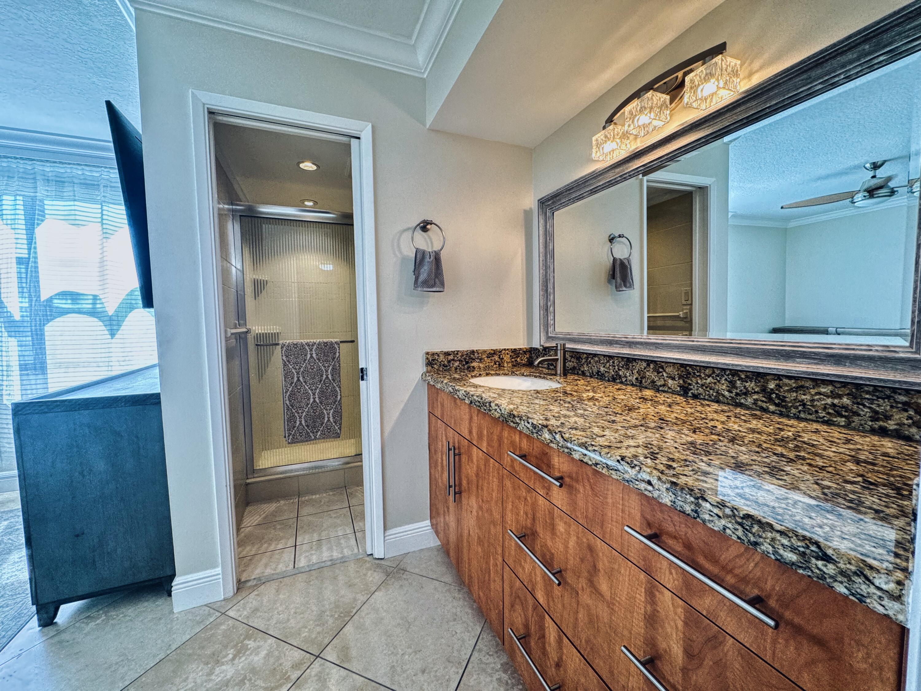 1915 Lavers Circle, Unit E209 Delray Beach, FL 33444 - Photo 15 of 20 a bathroom with a granite countertop sink and a mirror