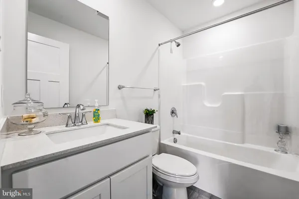 a bathroom with a granite countertop sink toilet a large mirror a bathtub and shower