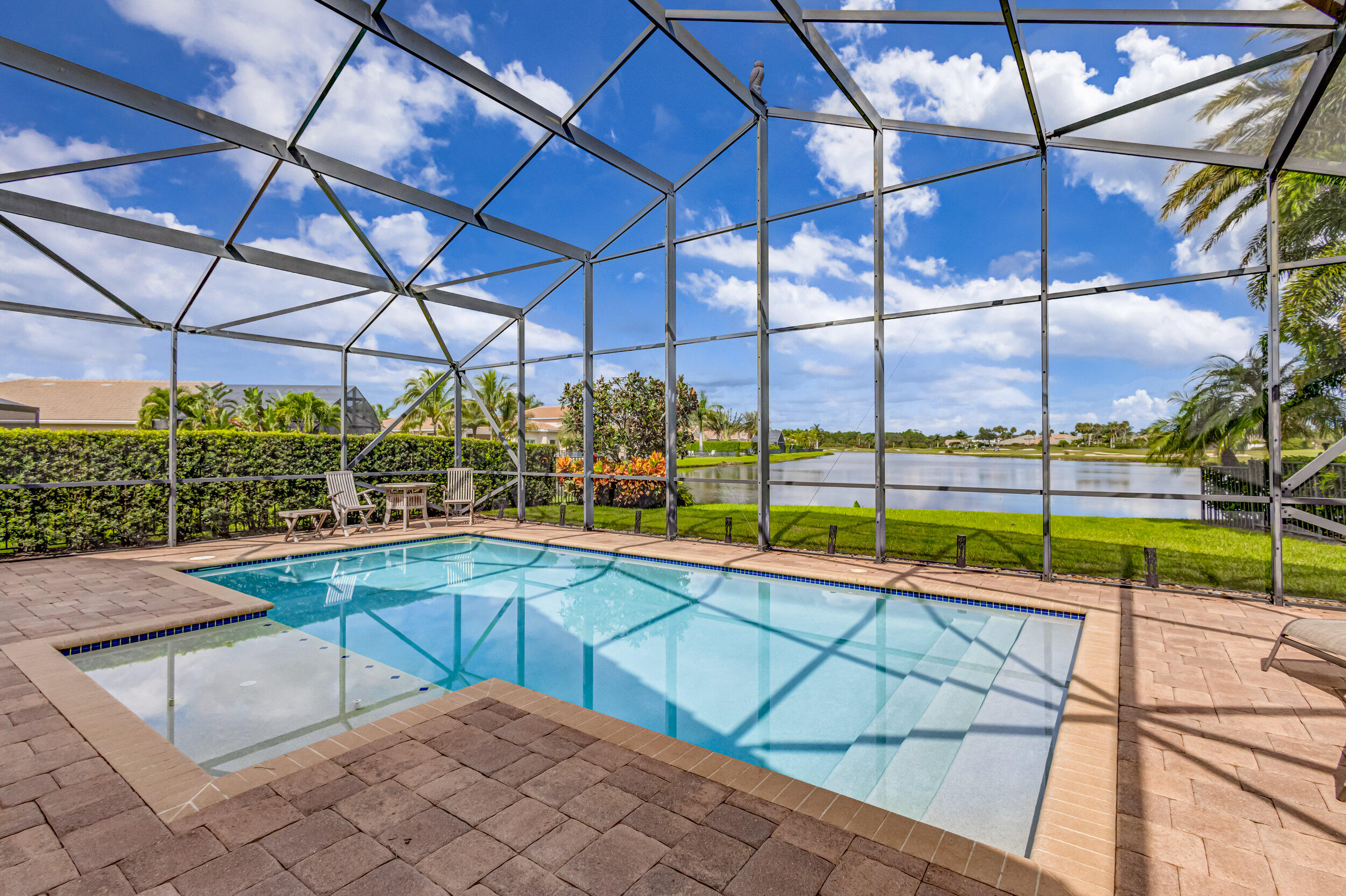 237 Carina Drive Jupiter, FL 33478 - Photo 20 of 73 a view of a swimming pool with a chair and tables in the patio