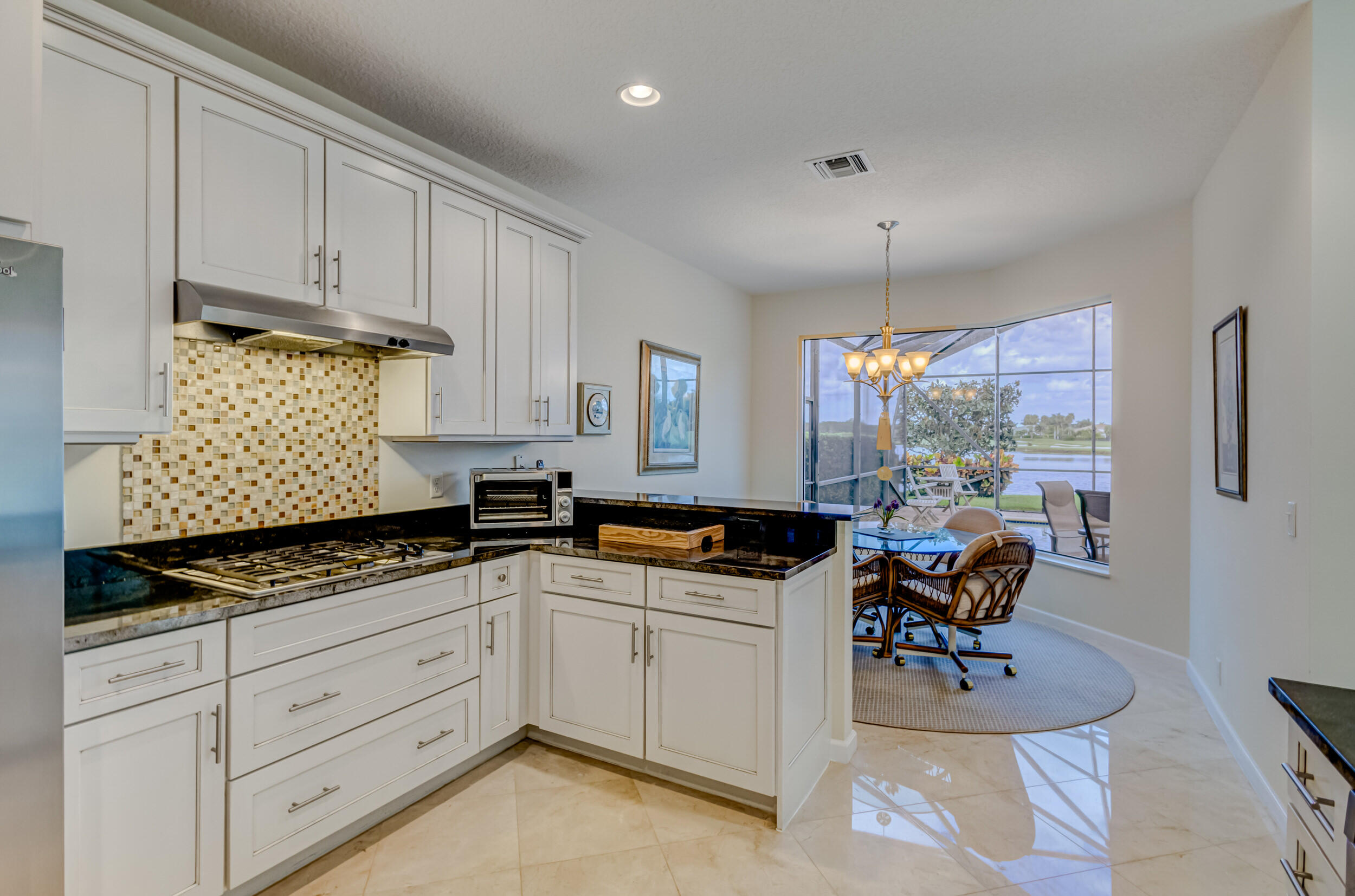 237 Carina Drive Jupiter, FL 33478 - Photo 26 of 73 a kitchen with granite countertop a stove a sink and white cabinets