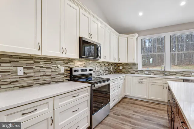 a kitchen with stainless steel appliances granite countertop a sink a stove and cabinets