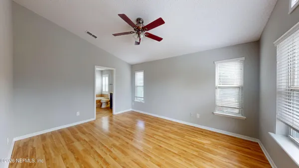 a view of empty room with wooden floor and fan