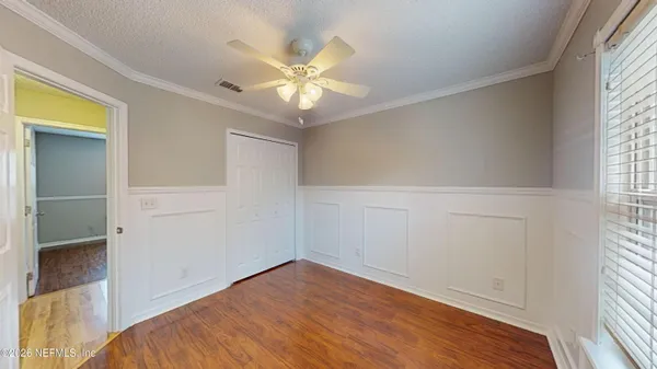 a view of an empty room with a window and wooden floor