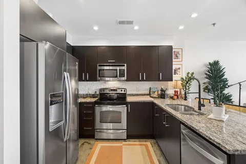 a kitchen with stainless steel appliances granite countertop a sink stove and refrigerator