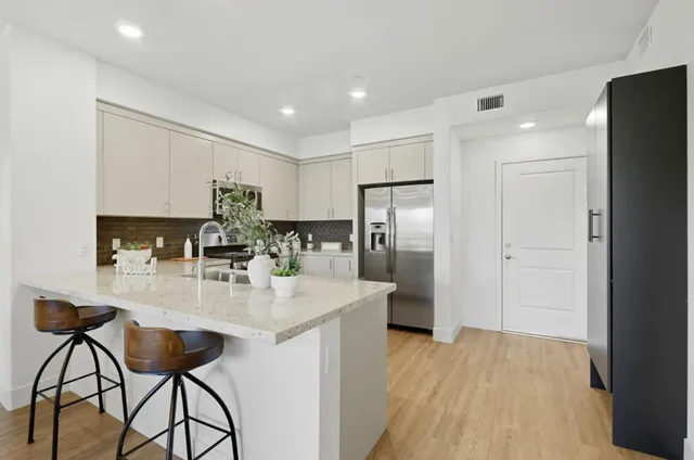 a kitchen with stainless steel appliances granite countertop a refrigerator a stove a sink dishwasher and white cabinets with wooden floor