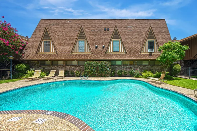 a view of swimming pool with lawn chairs and plants