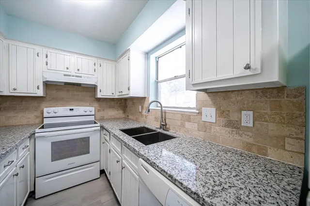 a kitchen with granite countertop white cabinets and white appliances
