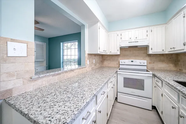 a kitchen with granite countertop a sink stove and cabinets