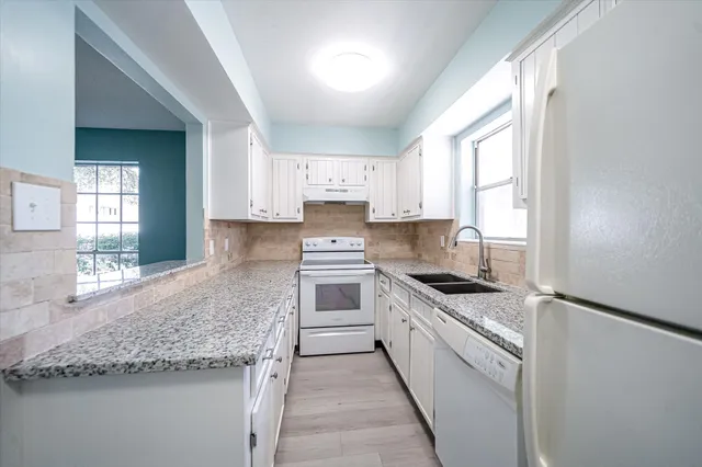 a kitchen with granite countertop a sink stove and cabinets