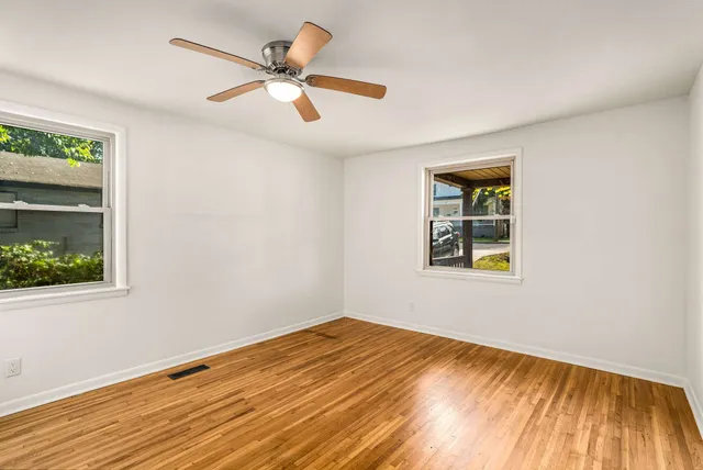 a view of empty room with wooden floor and fan