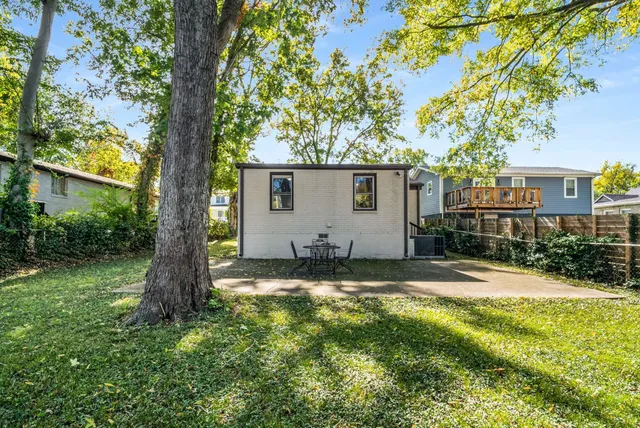 a backyard of a house with plants and large tree