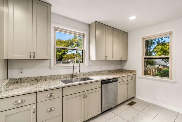 a kitchen with granite countertop white cabinets and window