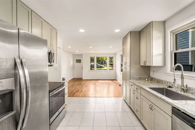 a large kitchen with stainless steel appliances kitchen island granite countertop a refrigerator a sink and dishwasher