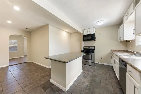 a large kitchen with stainless steel appliances granite countertop a lot of counter space and wooden floor