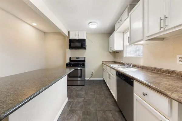 a kitchen with granite countertop a sink and a stove