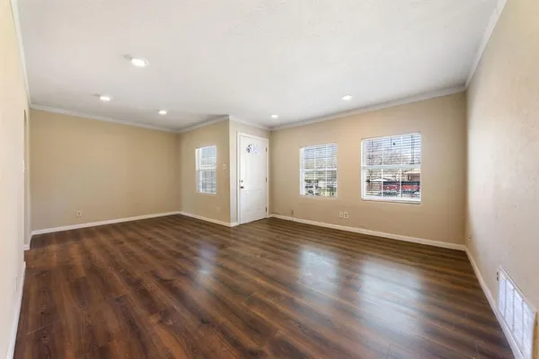 an empty room with wooden floor and windows
