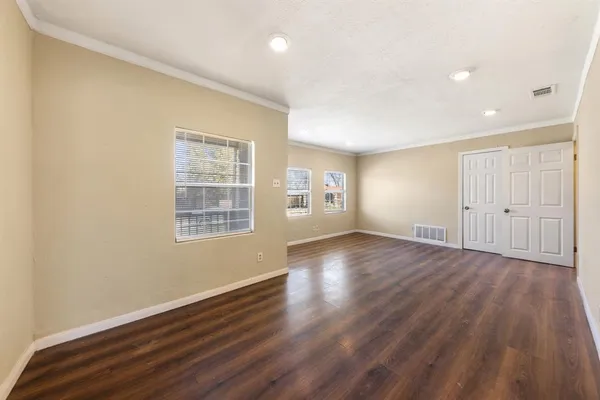 an empty room with wooden floor and windows