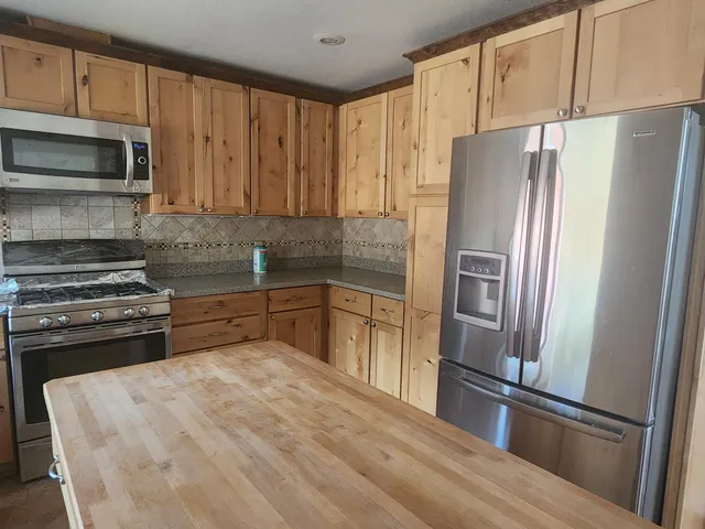 a kitchen with granite countertop a refrigerator and a stove top oven