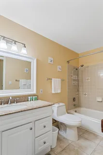 a bathroom with a granite countertop sink mirror vanity bathtub and toilet