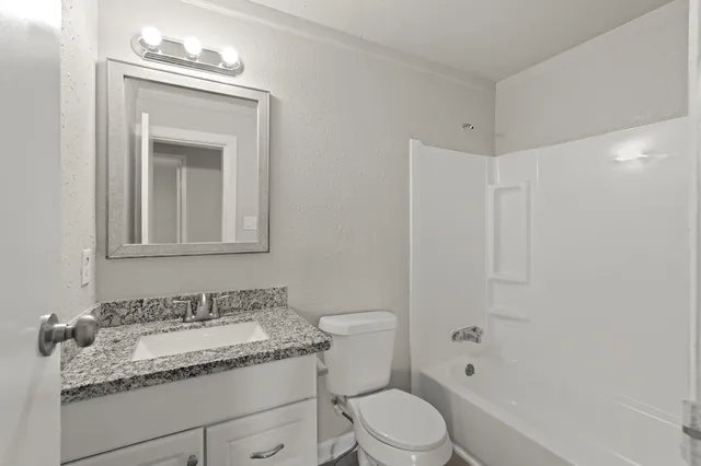 a bathroom with a granite countertop sink a toilet and shower