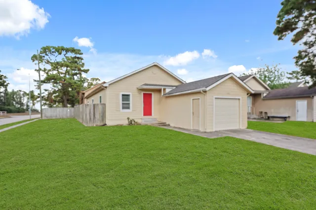 a view of a yard in front of a house with plants and large tree