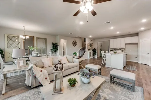 a living room with furniture kitchen view and a chandelier