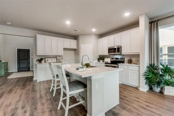 a kitchen with a dining table chairs appliances and cabinets