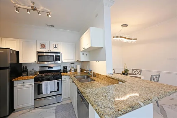 a kitchen with stainless steel appliances kitchen island granite countertop a refrigerator and microwave