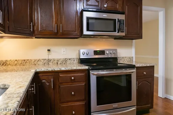 a kitchen with granite countertop cabinets stainless steel appliances and wooden floor